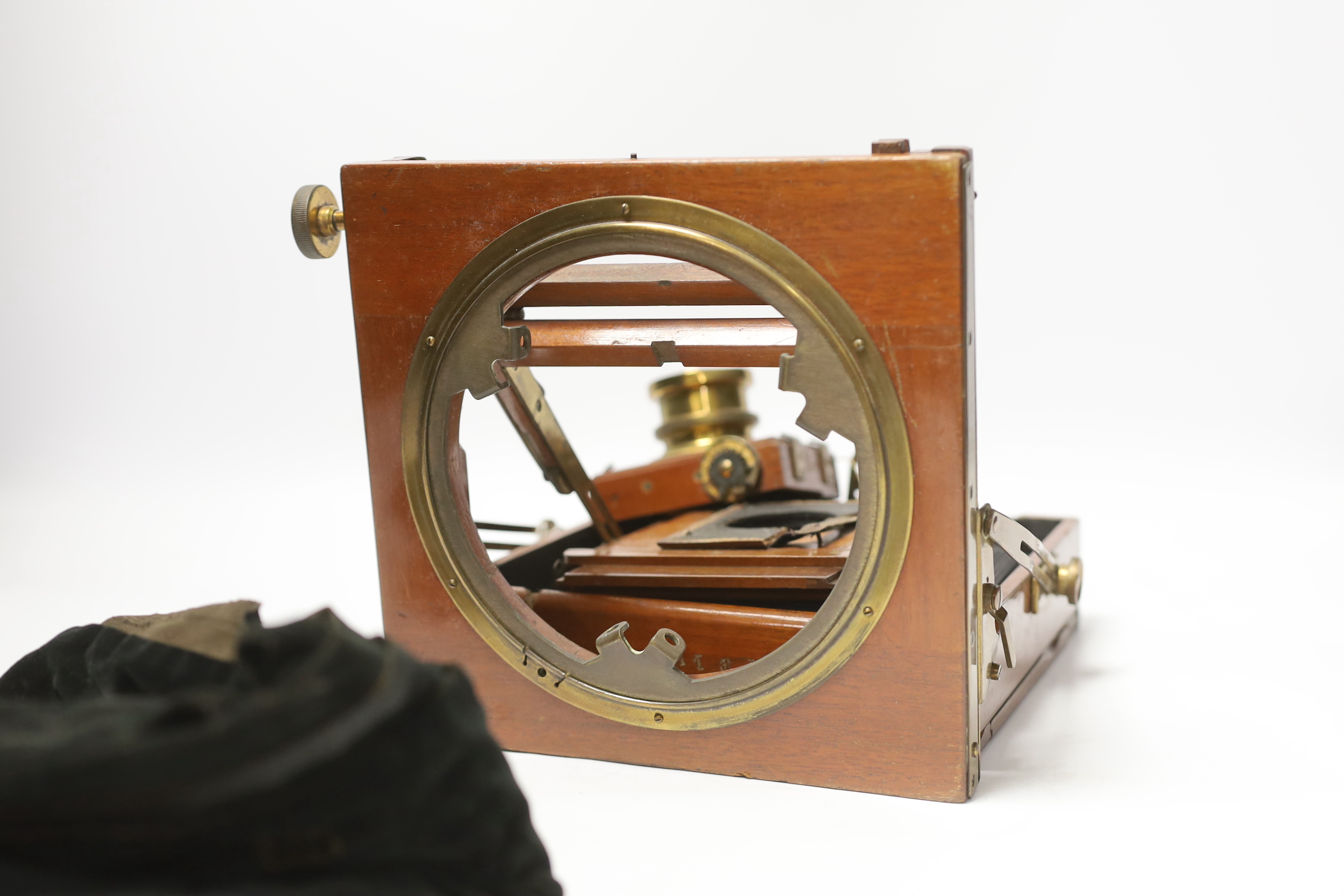 An early 20th century brass and mahogany half plate bellows camera with a lens and a shutter action by Thornton Pickard, on an oak tripod